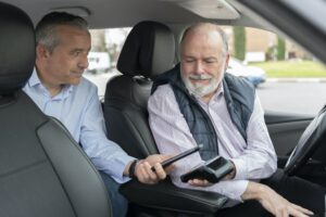 middle-aged passenger in back seat paying with mobile app to elderly driver